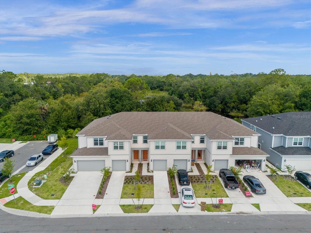 an aerial view of residential houses with outdoor space and trees