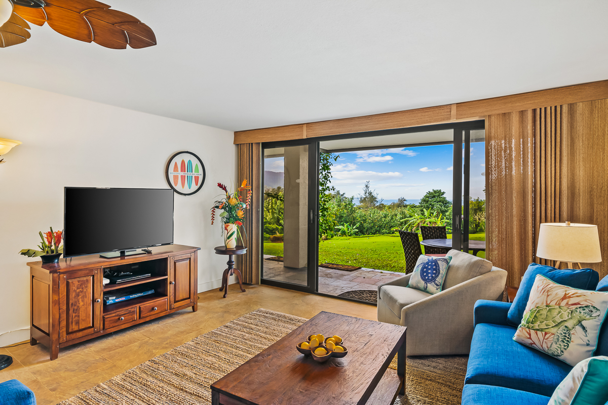 a living room with furniture a flat screen tv and a floor to ceiling window