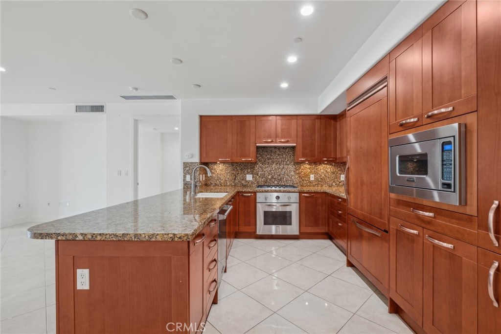 a kitchen with stainless steel appliances granite countertop a stove refrigerator sink and microwave