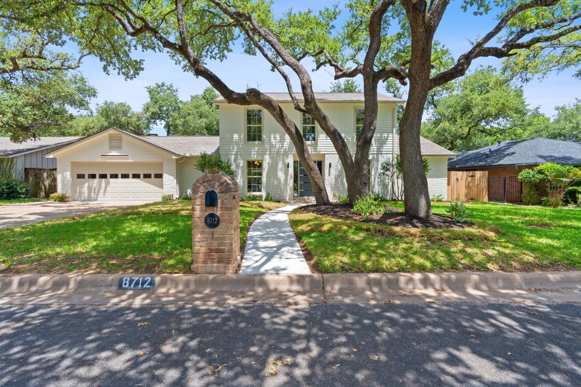 a front view of a house with a yard and an tree