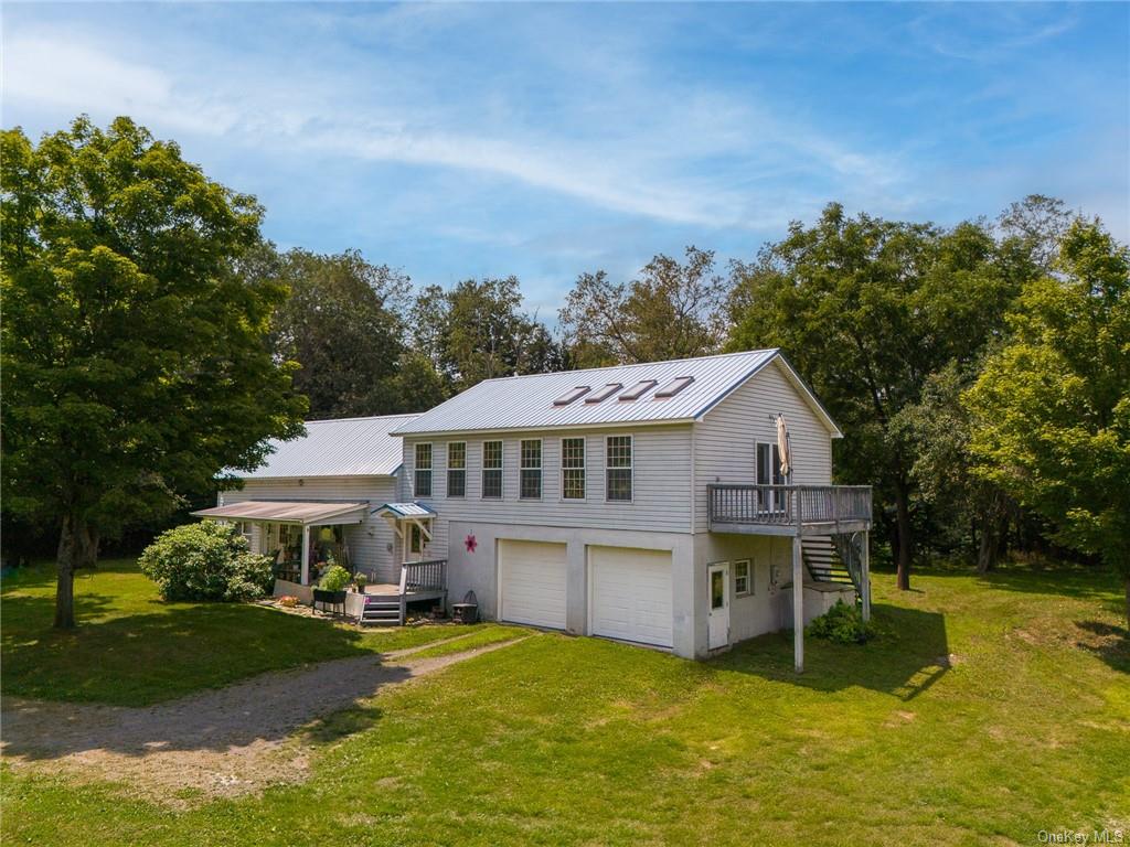 View of front of home with a garage, a deck, and a front yard