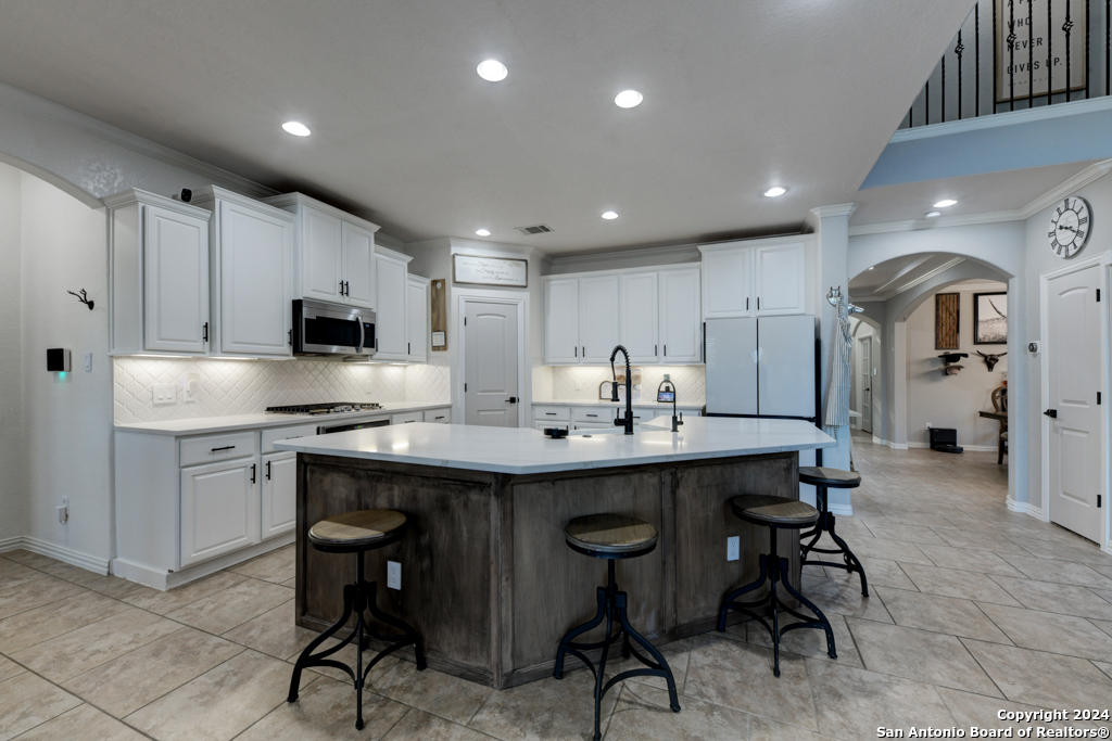 a kitchen with stainless steel appliances kitchen island granite countertop a table chairs sink and cabinets