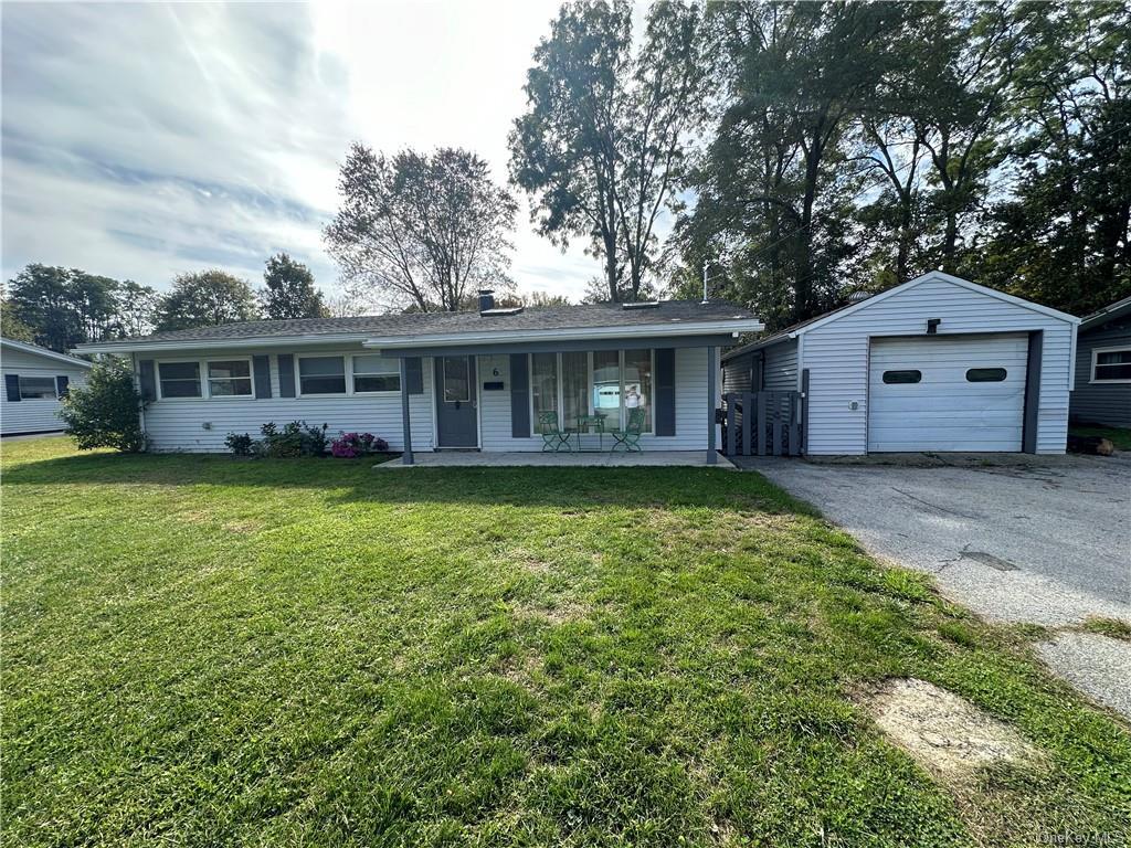 Single story home with covered porch, a garage, a front lawn, and an outdoor structure