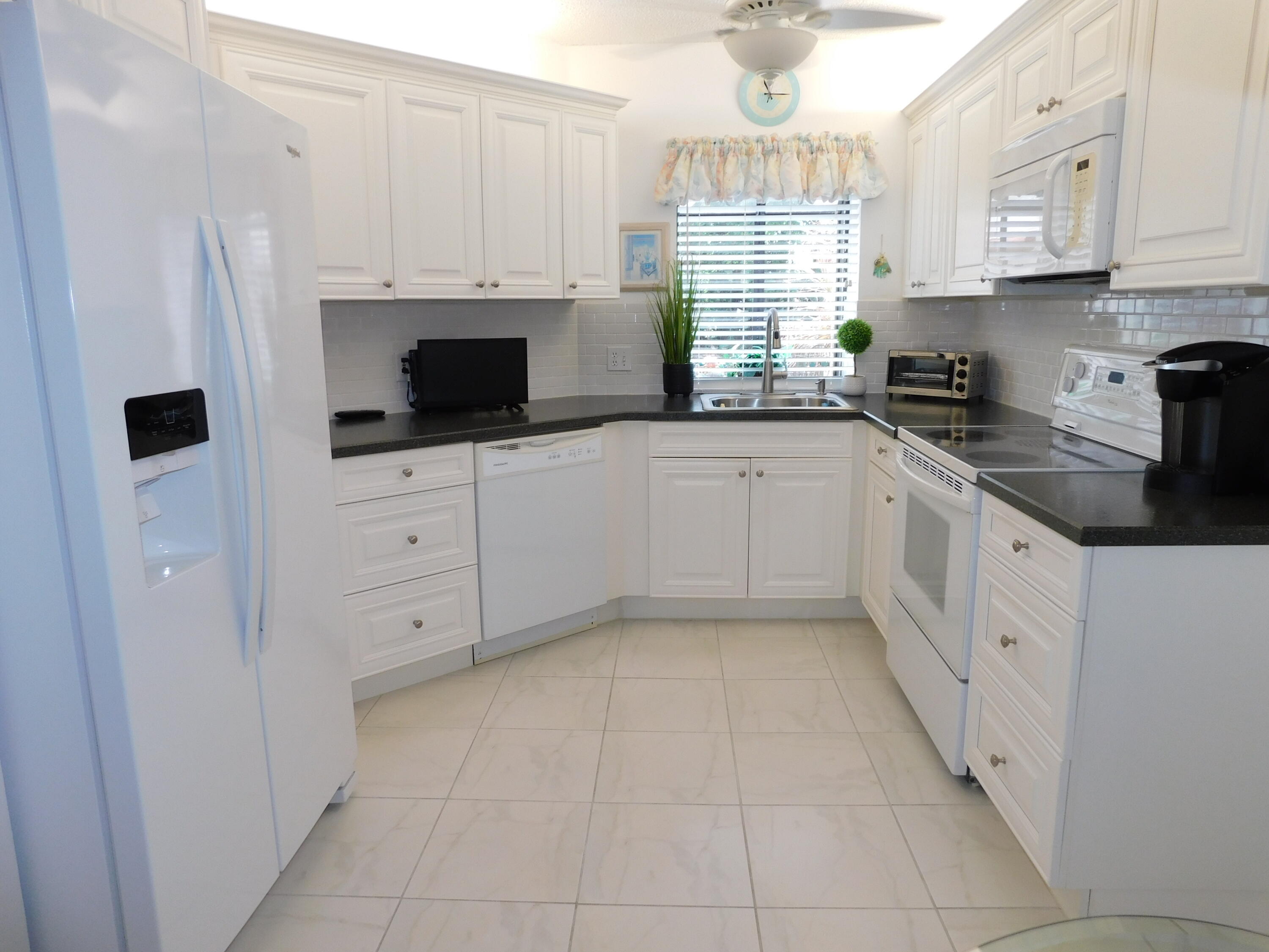 a kitchen with white cabinets and window