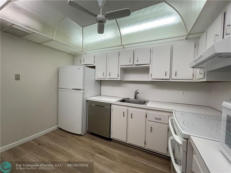 a kitchen with a sink a refrigerator and white cabinets