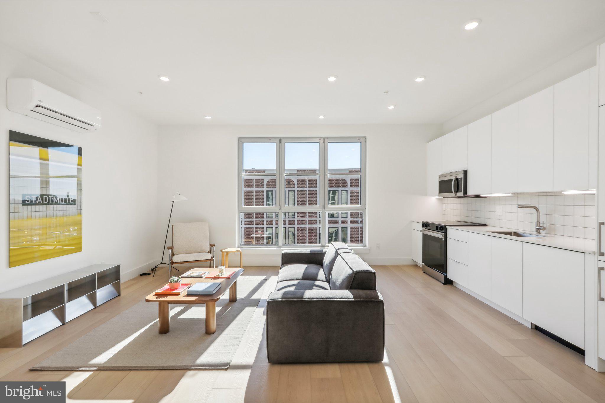 a living room with furniture and a kitchen area with wooden floor