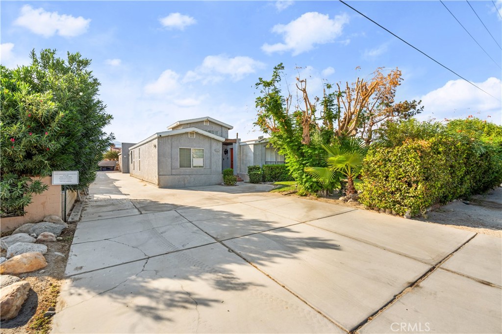 a front view of a house with a yard and trees in the background