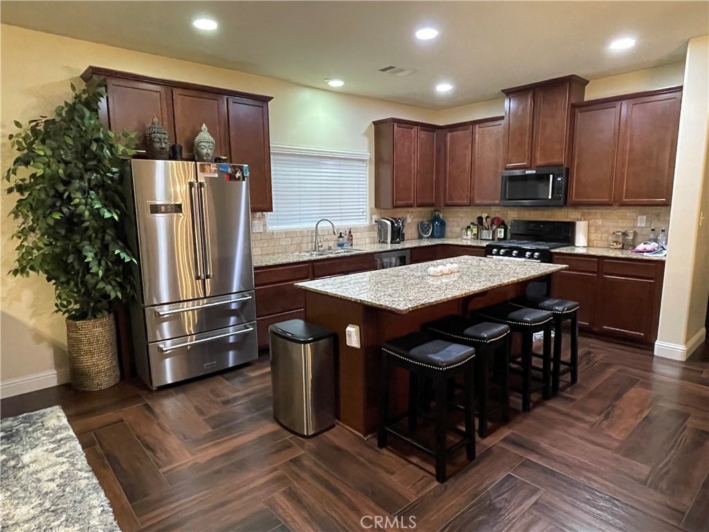 a kitchen with stainless steel appliances granite countertop a refrigerator a sink and a stove