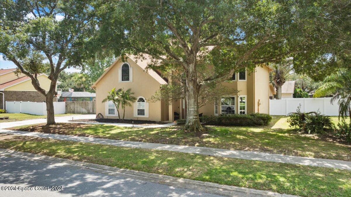 a front view of a house with a yard and large trees