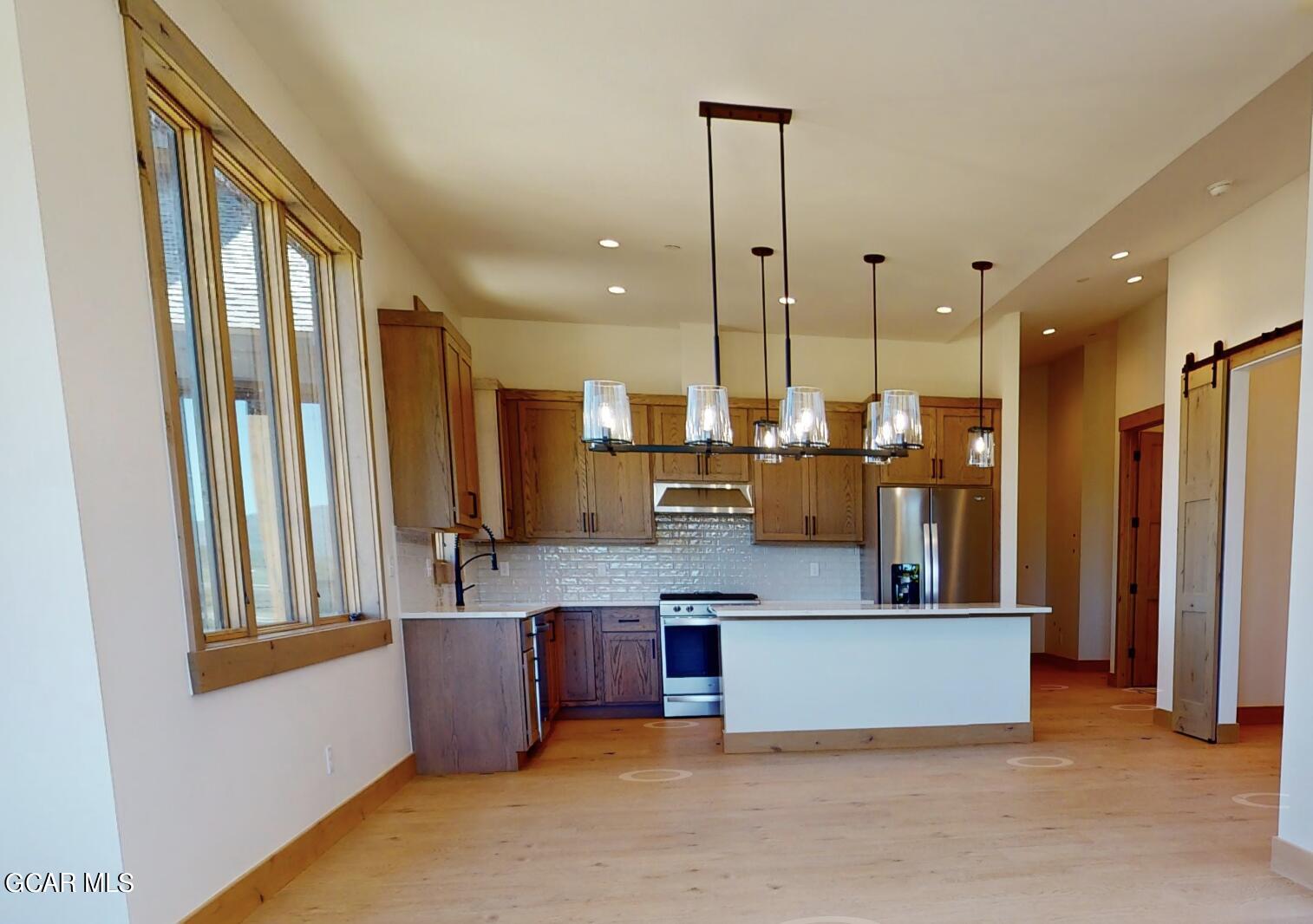 a large kitchen with stainless steel appliances kitchen island a large counter top and a view of living room