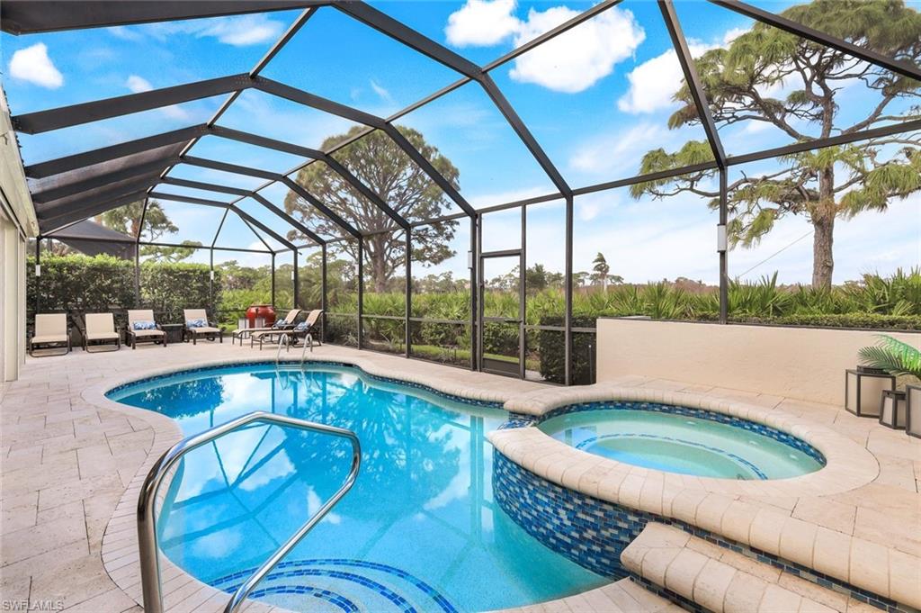 View of swimming pool with an in ground hot tub, a patio area, and glass enclosure