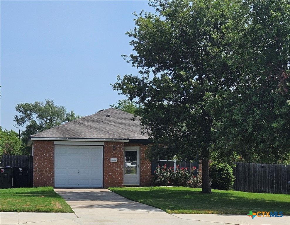 a front view of a house with a garden and trees