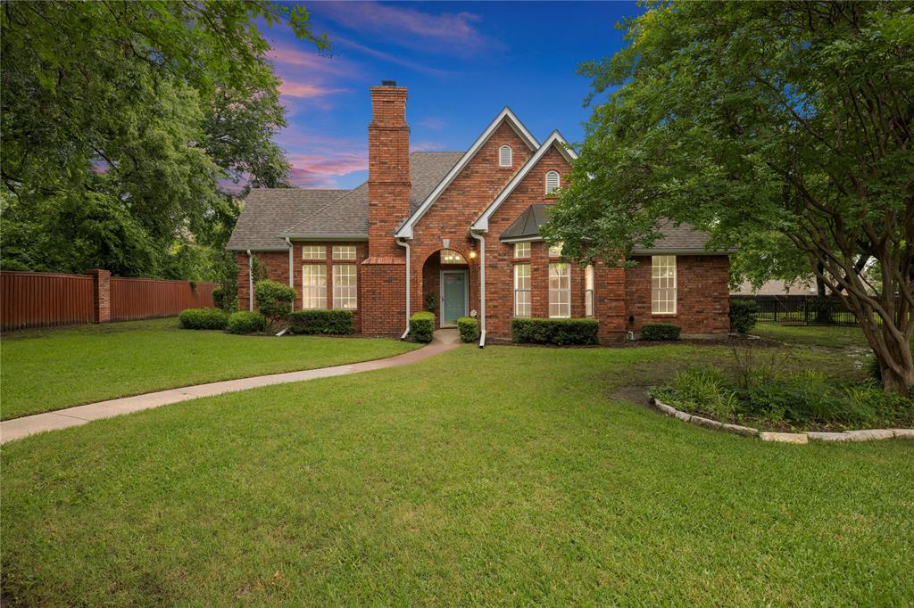 a view of a house next to a big yard and large trees