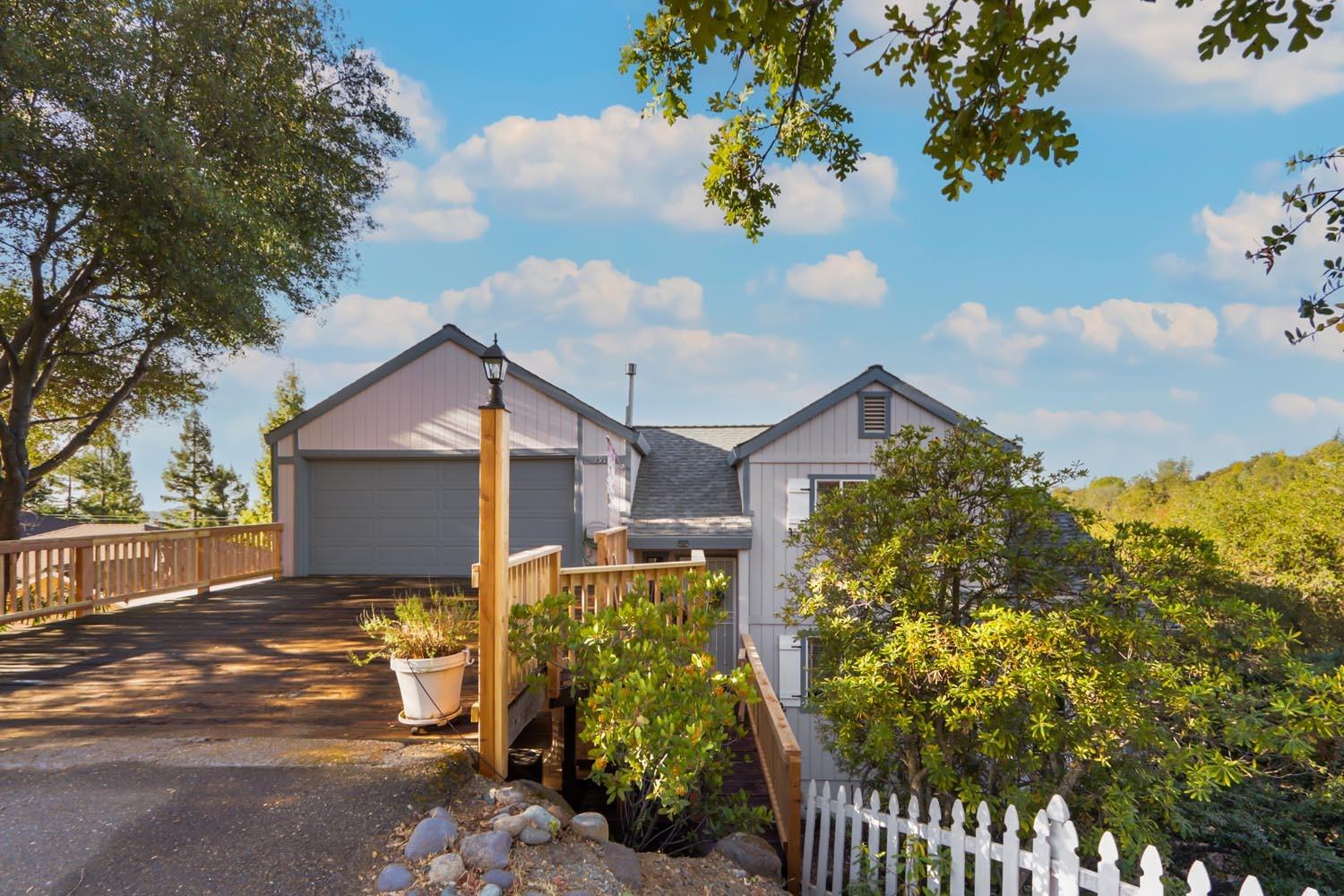 a front view of a house with a yard and covered with trees