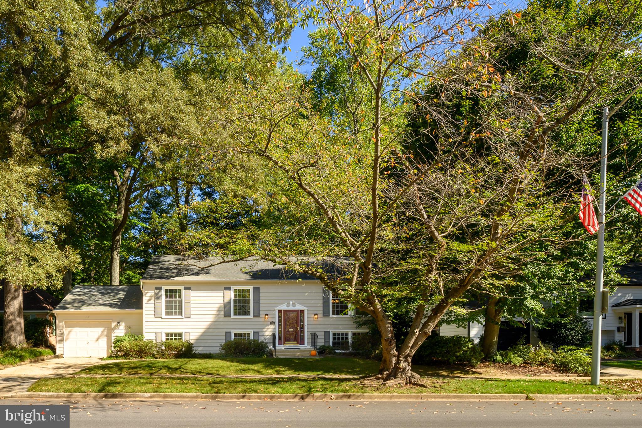 a view of a white house with a yard and large trees