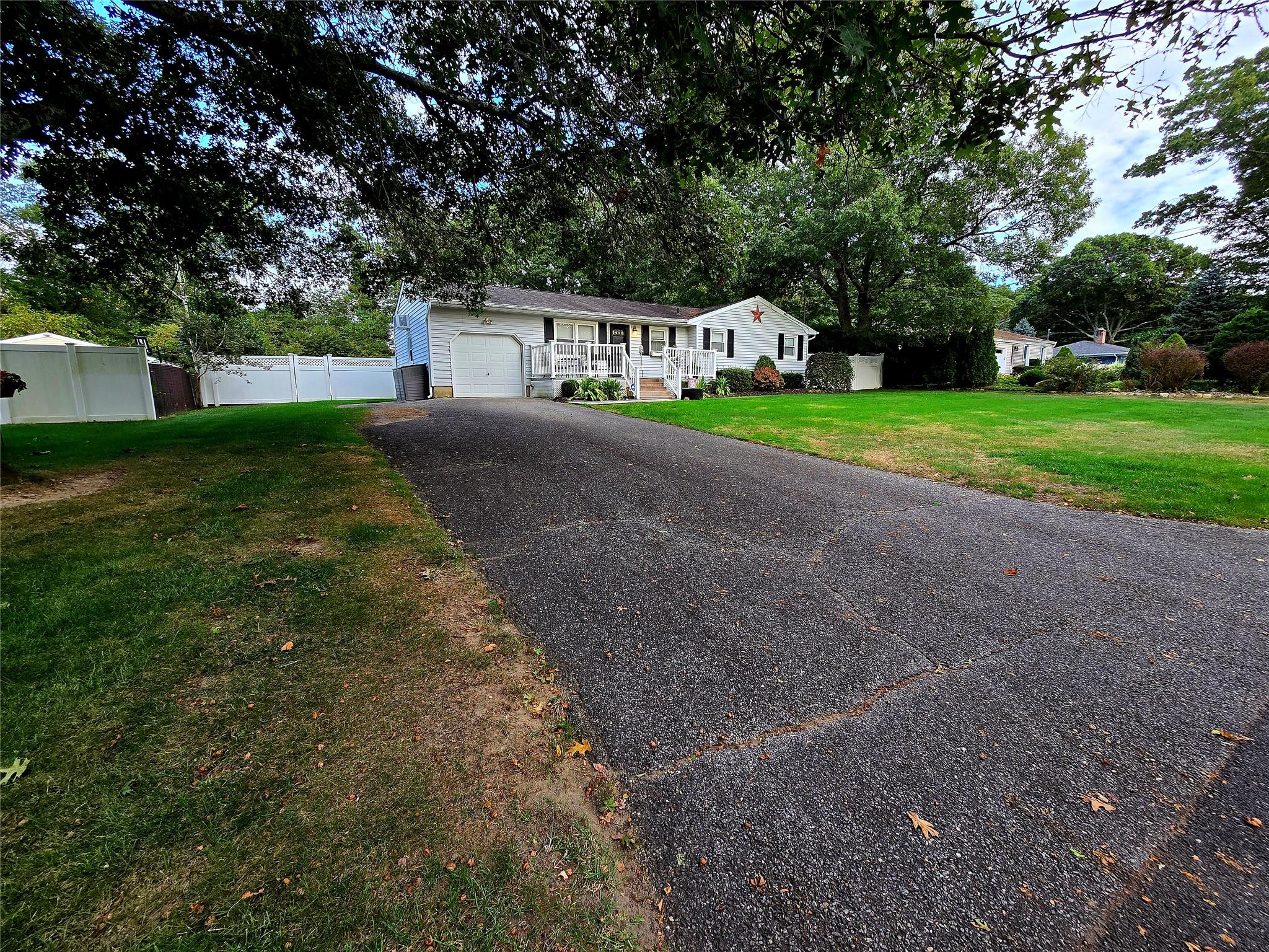 Ranch-style home featuring a front yard, a porch, and a garage