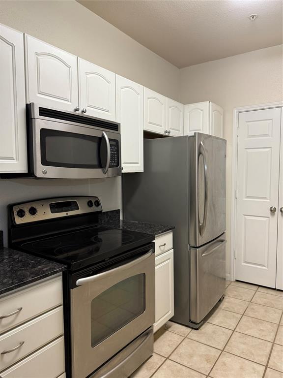 a kitchen with granite countertop a refrigerator and a stove top oven