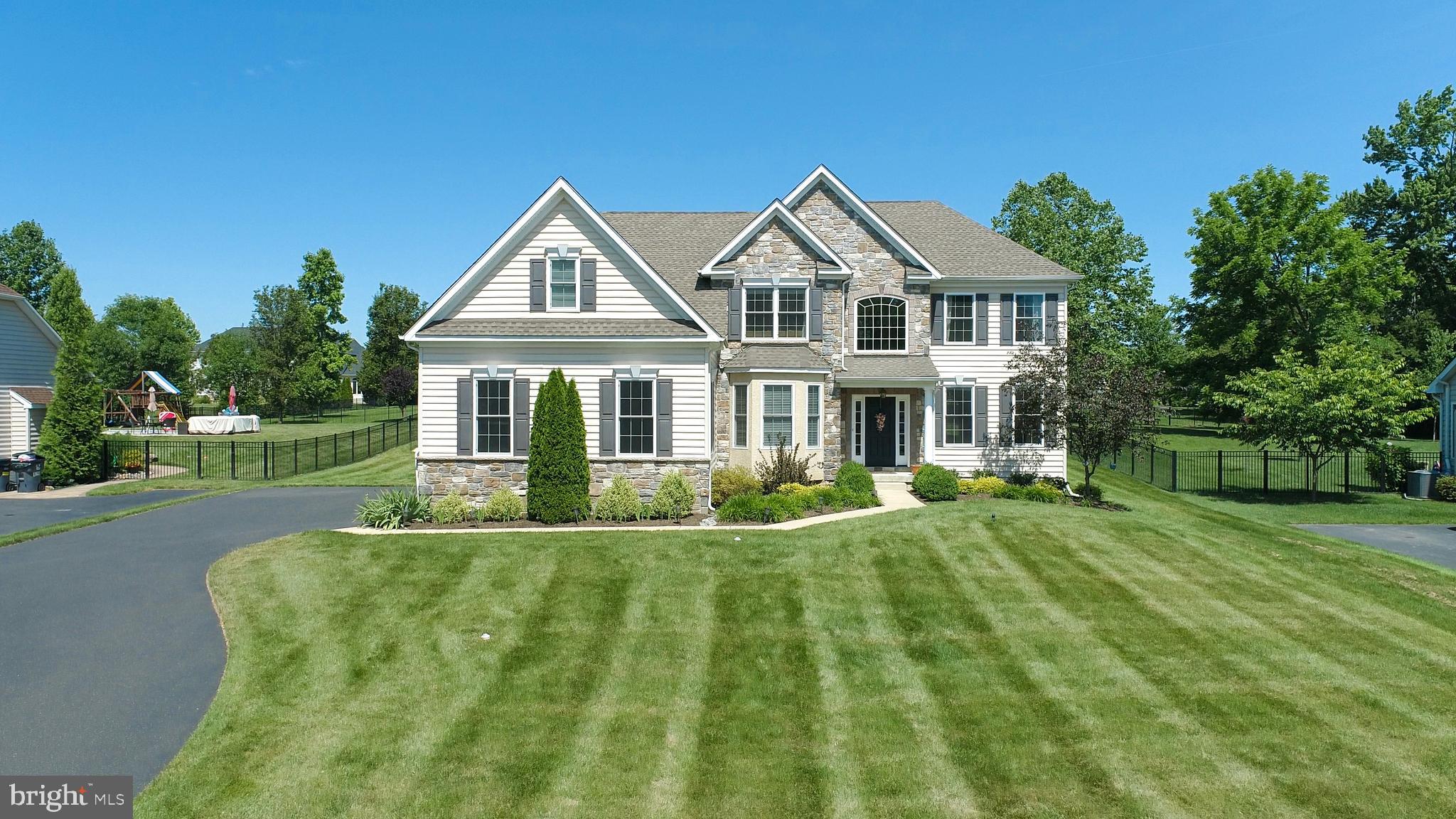 a view of a house with a big yard plants and large trees