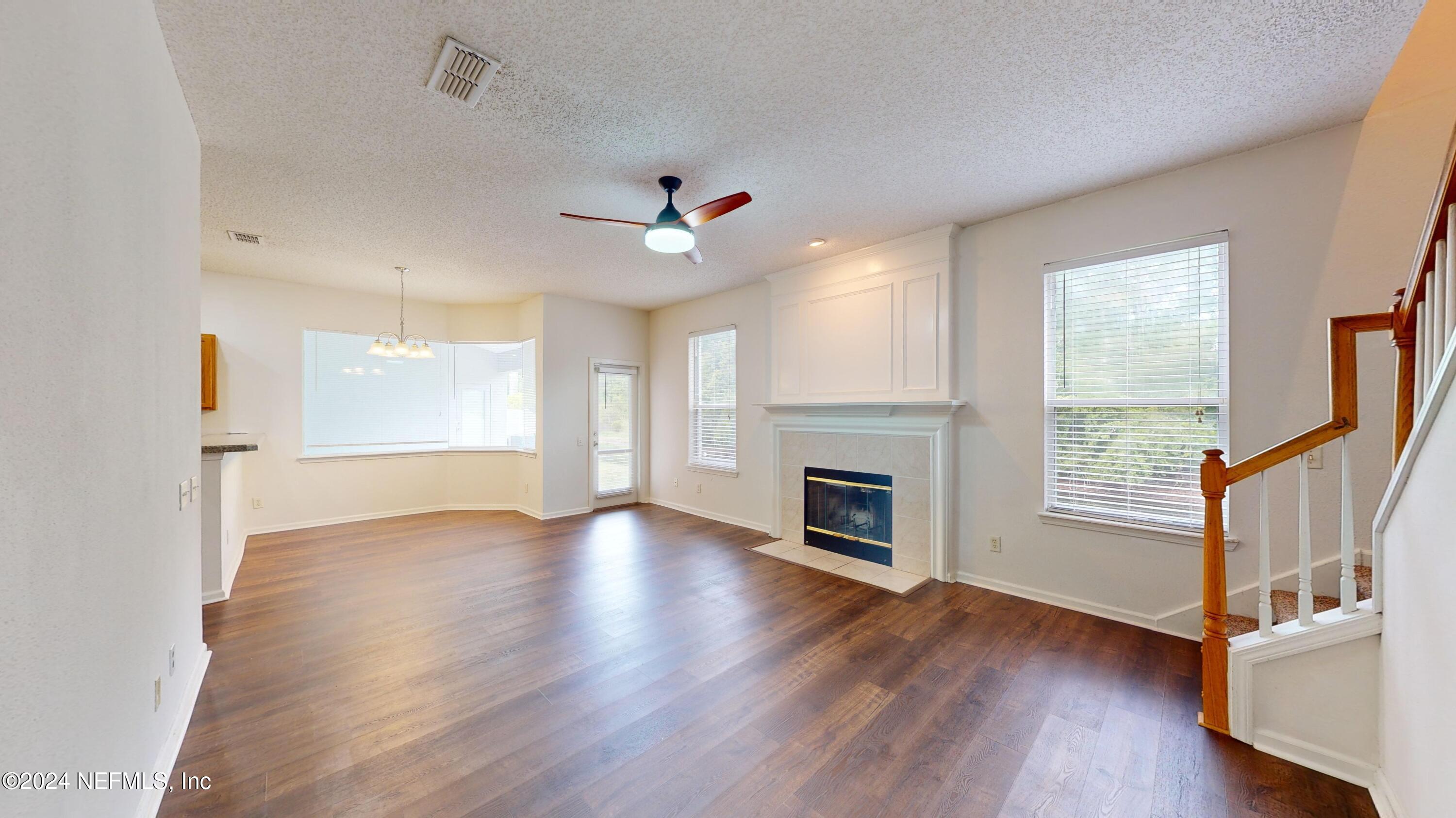 an empty room with wooden floor fireplace and windows