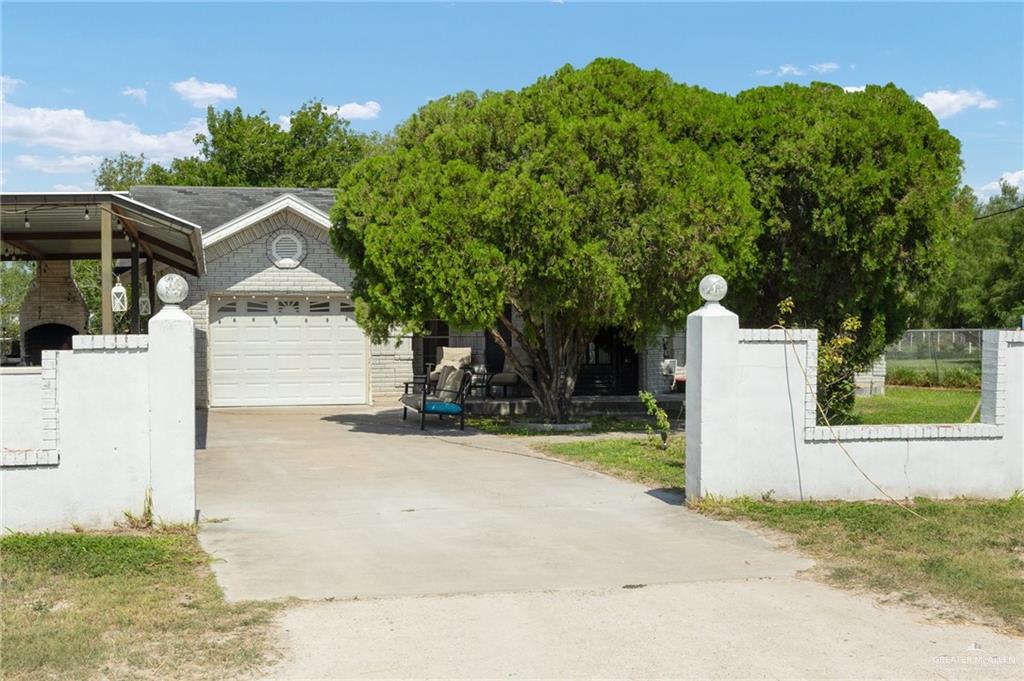 a view of a house with a yard and large tree