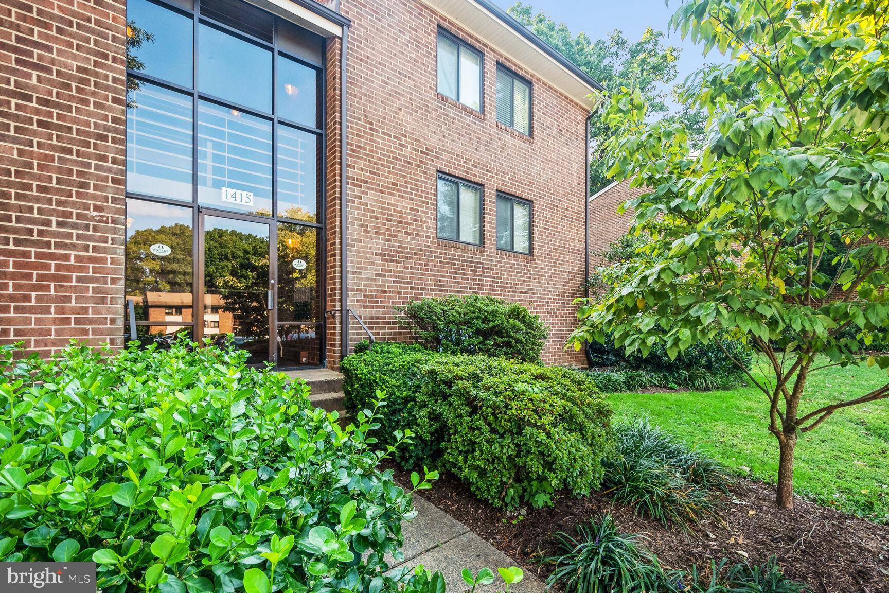 a view of a brick house with a yard and plants