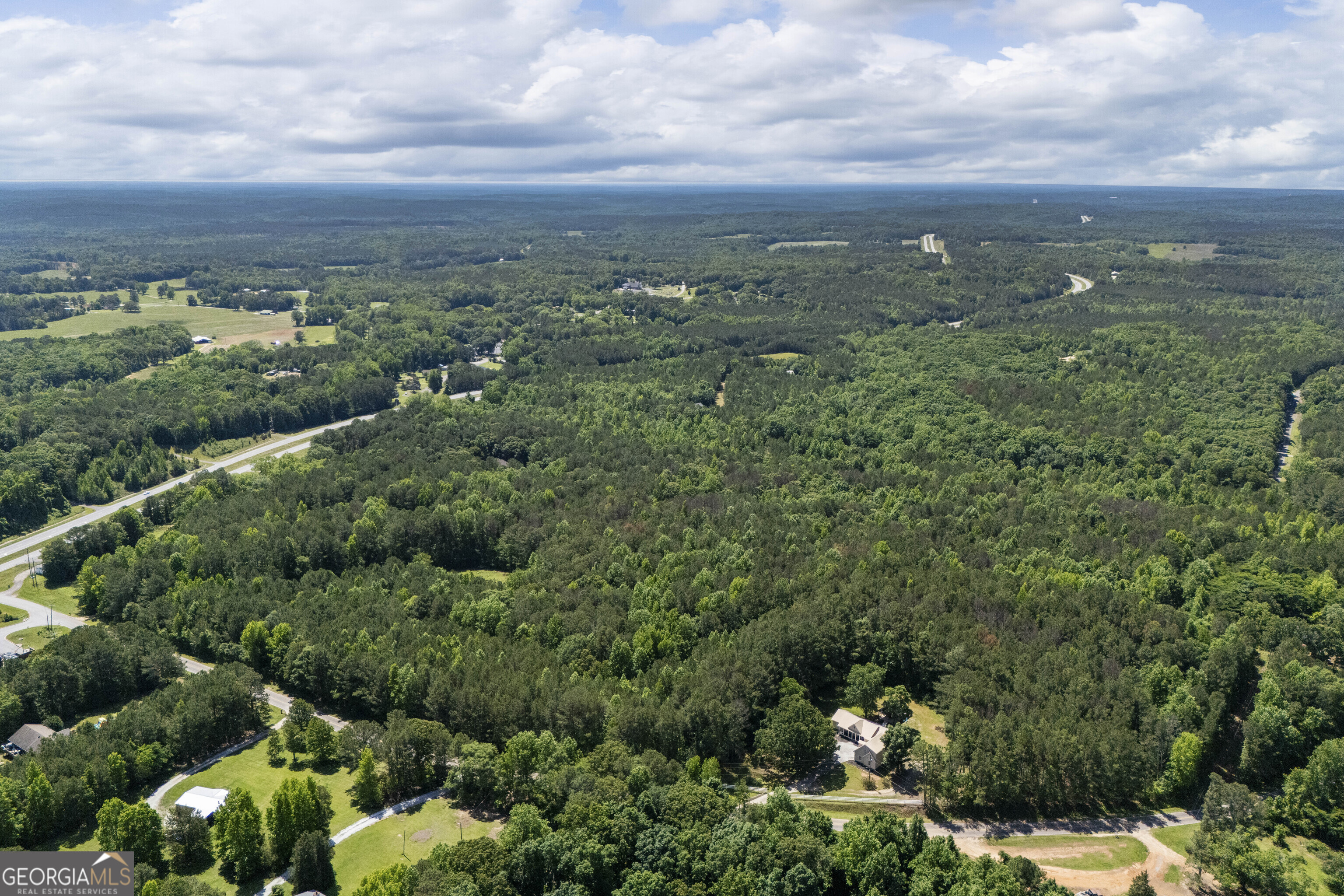 an aerial view of residential house with outdoor space and trees all around