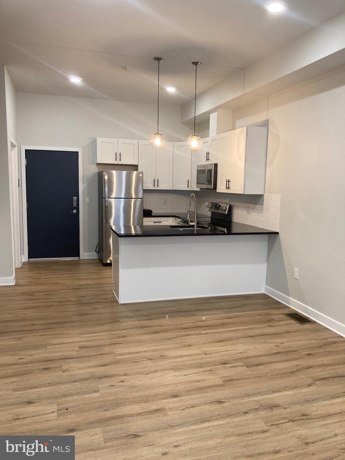 a view of a kitchen with kitchen island a sink stainless steel appliances and cabinets