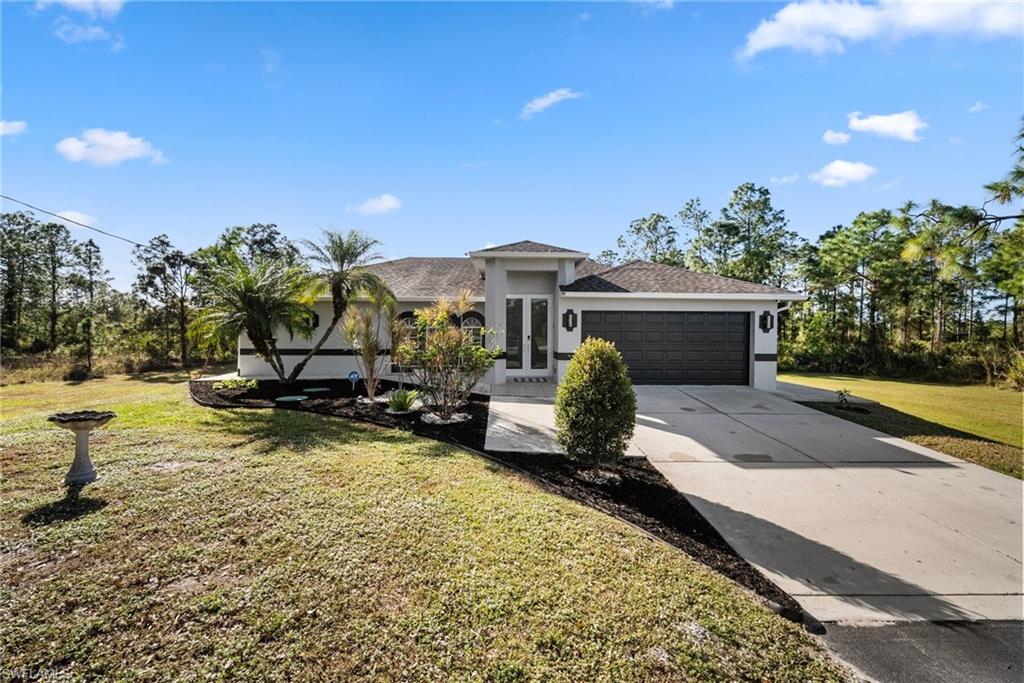 View of front of property featuring a garage, a front yard, and french doors