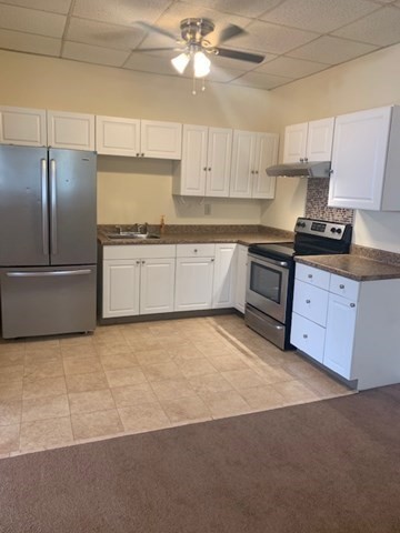 a kitchen with granite countertop a refrigerator a sink and dishwasher