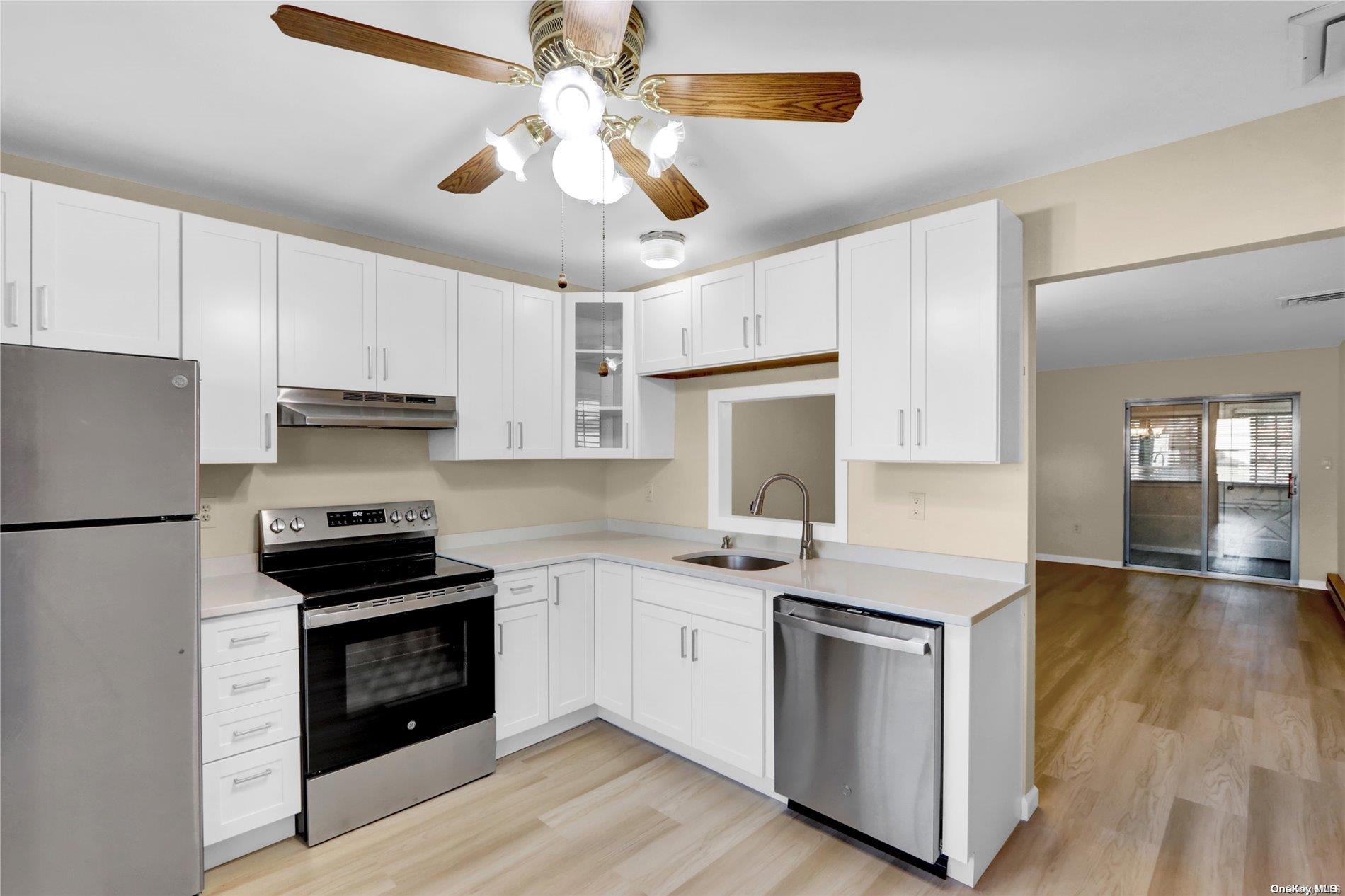 a kitchen with stainless steel appliances a stove a sink and white cabinets