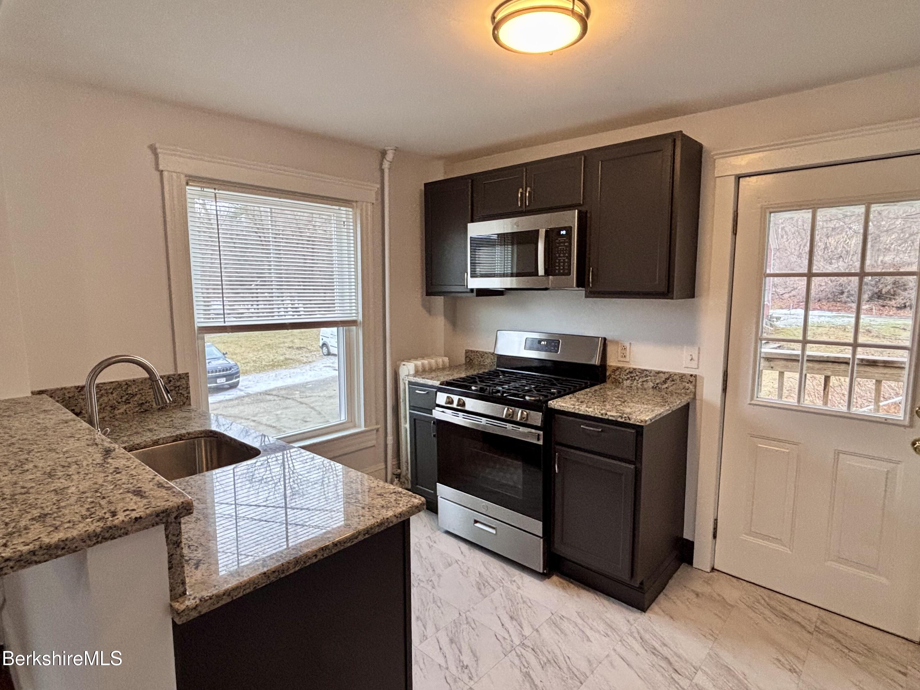 a kitchen with stainless steel appliances granite countertop a stove microwave and sink