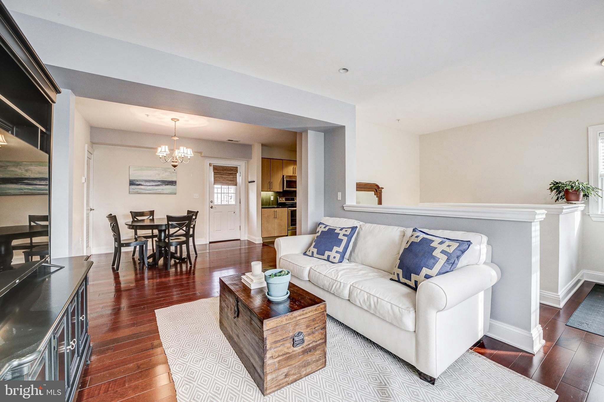 a living room with furniture and a dining table with wooden floor