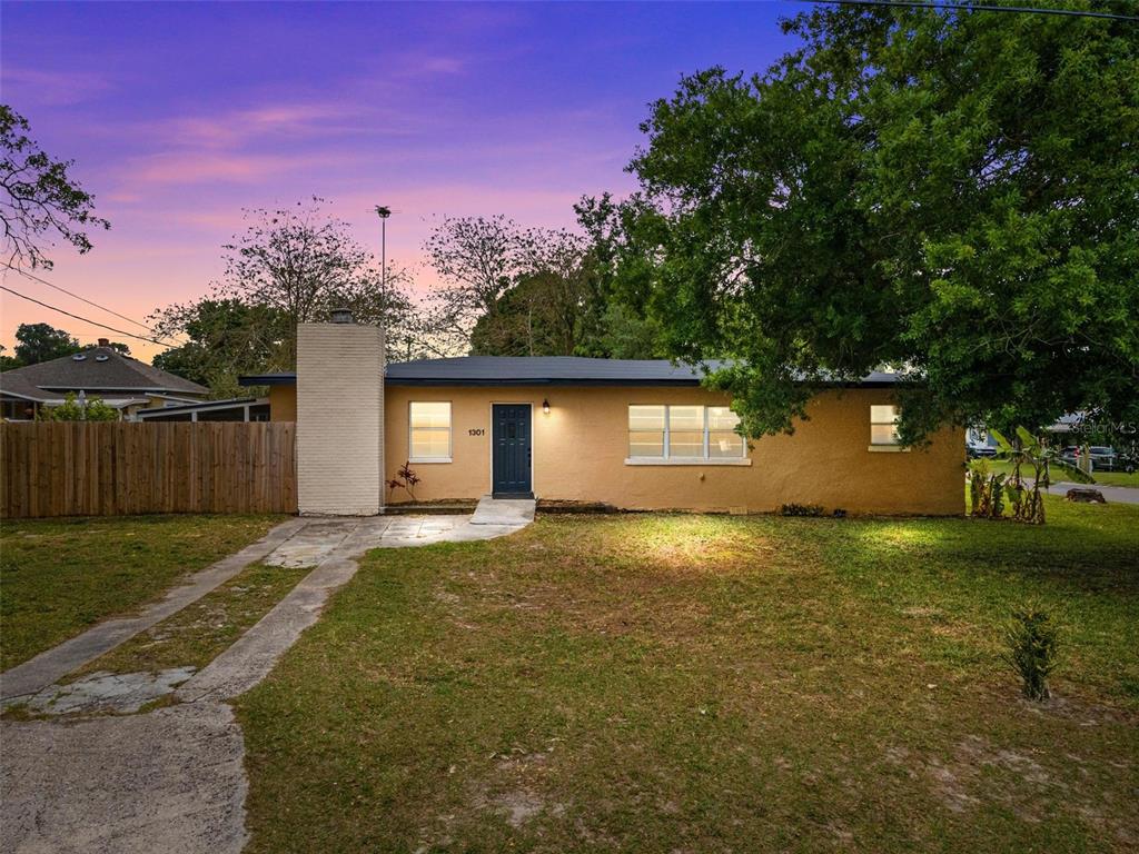 a view of a house with a yard and a large tree