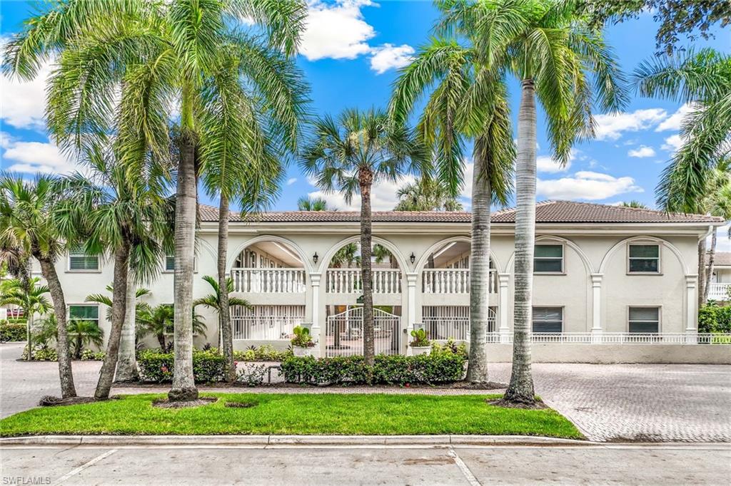 a view of a white house with a big yard and palm trees