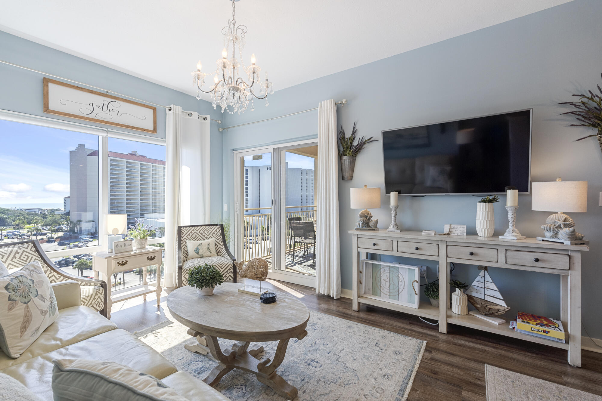 a living room with furniture a flat screen tv and a chandelier