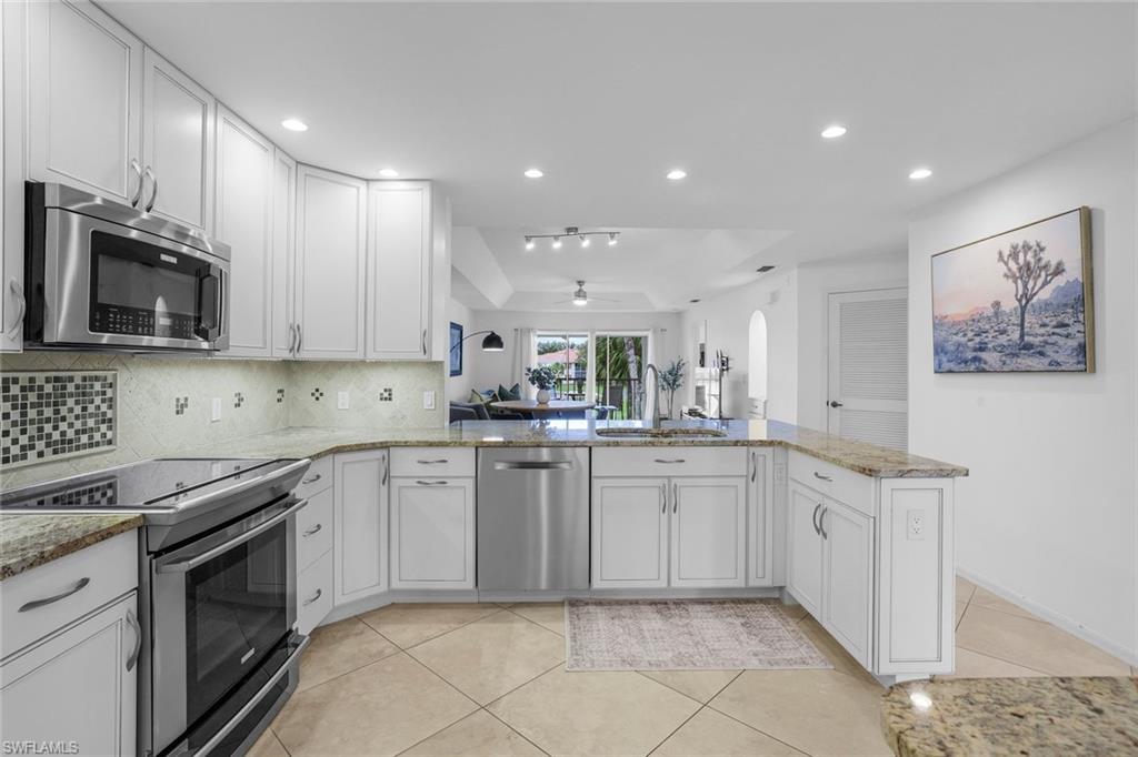 Kitchen featuring white cabinets, sink, ceiling fan, appliances with stainless steel finishes, and kitchen peninsula