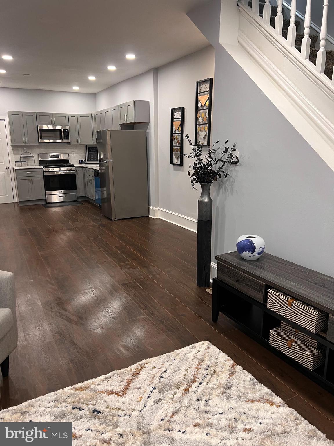 a living room with stainless steel appliances kitchen island furniture and wooden floor