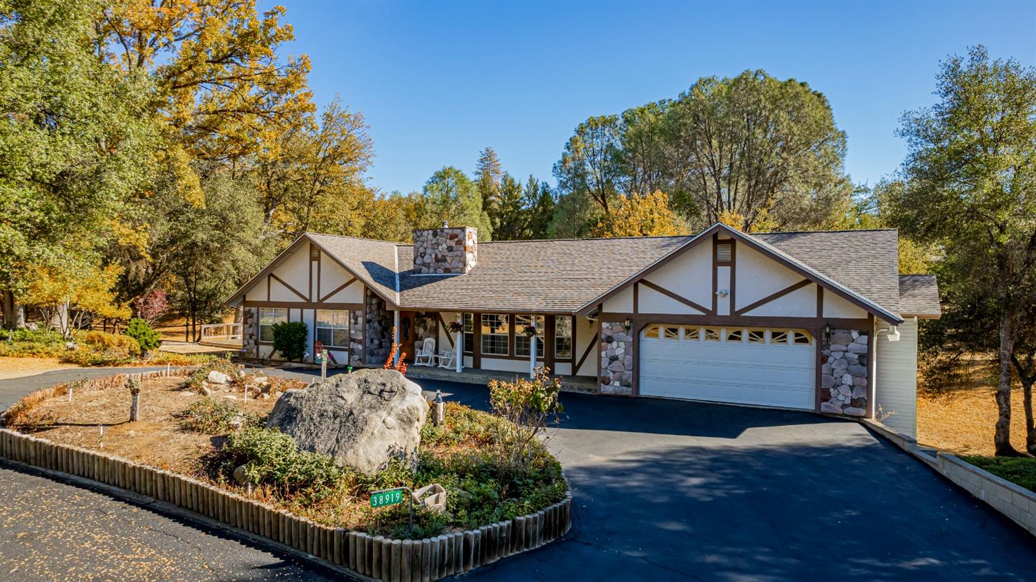 a front view of a house with a yard outdoor seating and covered with trees