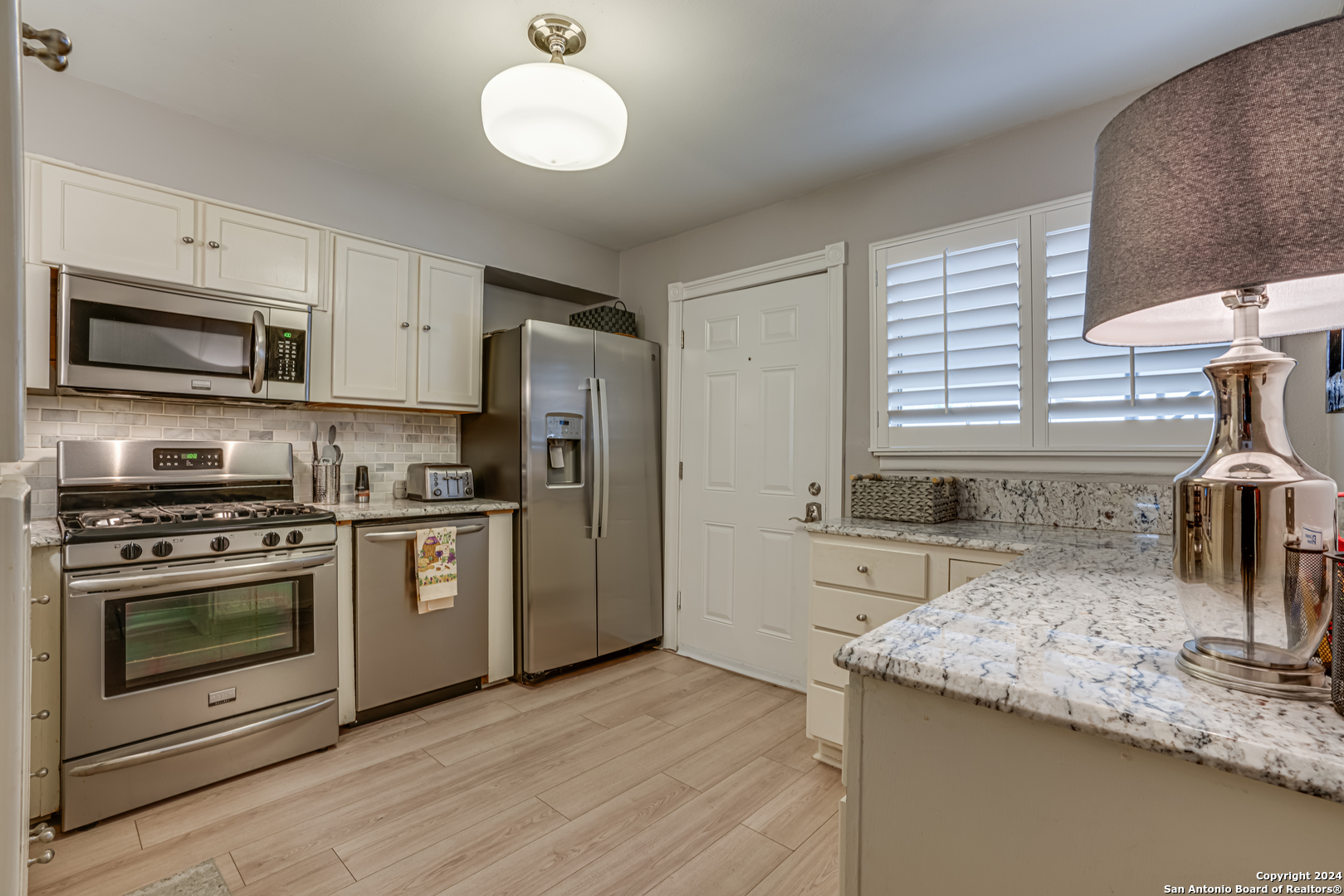 a kitchen with granite countertop a stove a sink and a microwave