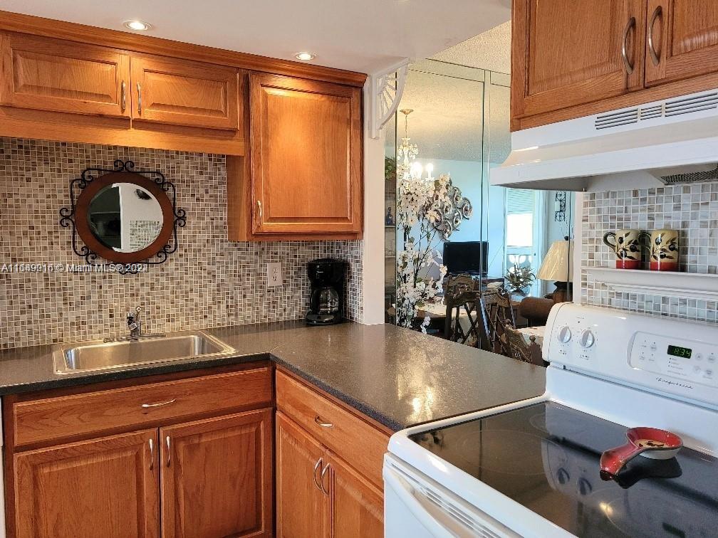 a kitchen with kitchen island granite countertop a sink and a refrigerator