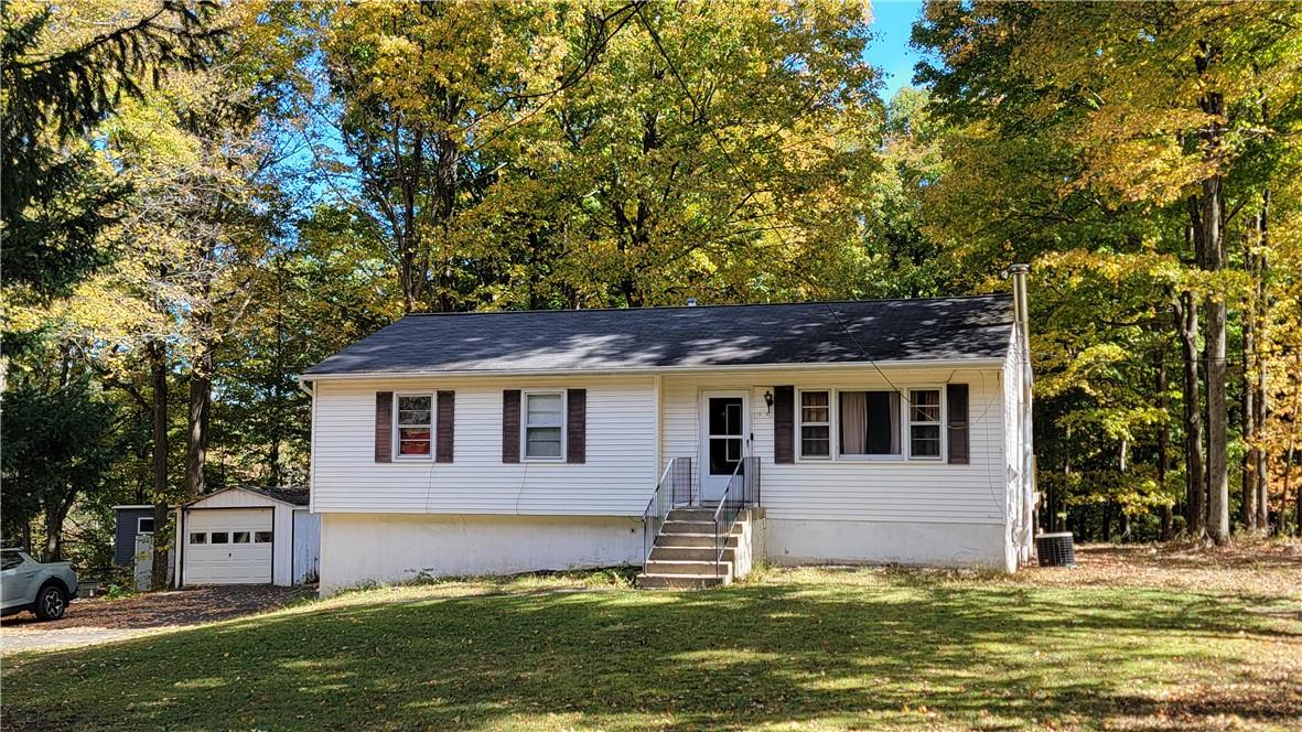 a front view of house with yard and trees in the background