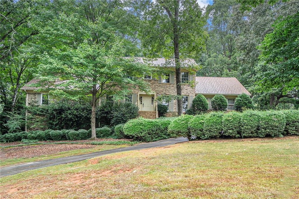 a front view of a house with a yard and large trees