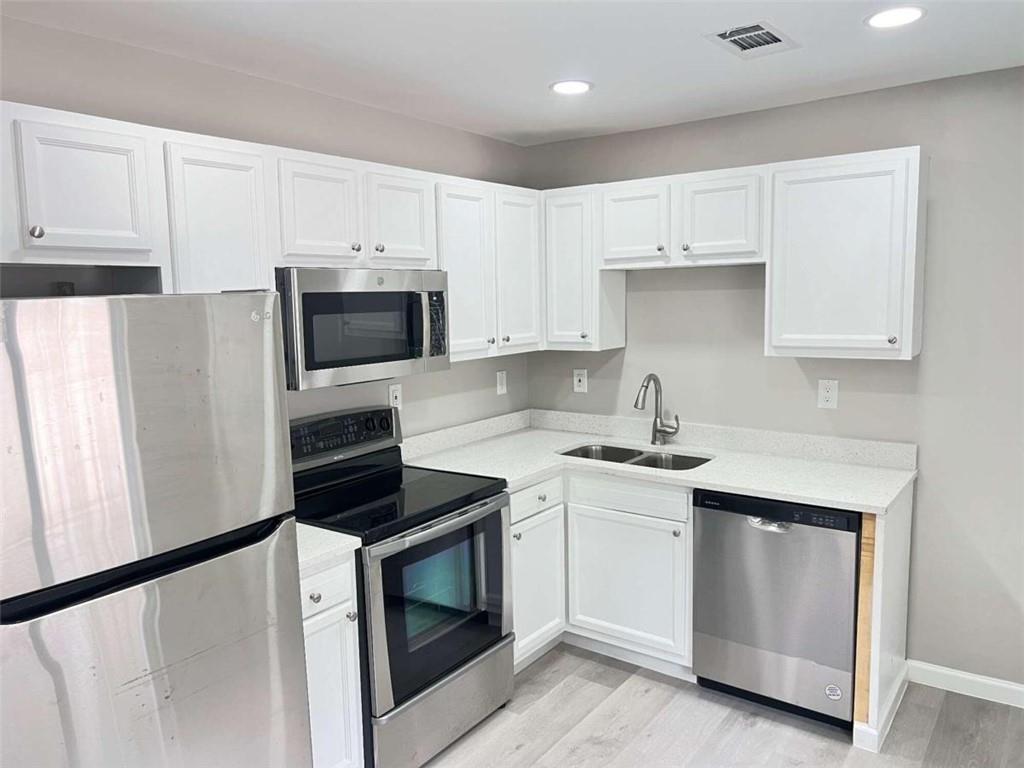 a kitchen with white cabinets and stainless steel appliances