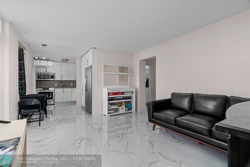 a living room with furniture and a dining table with kitchen view