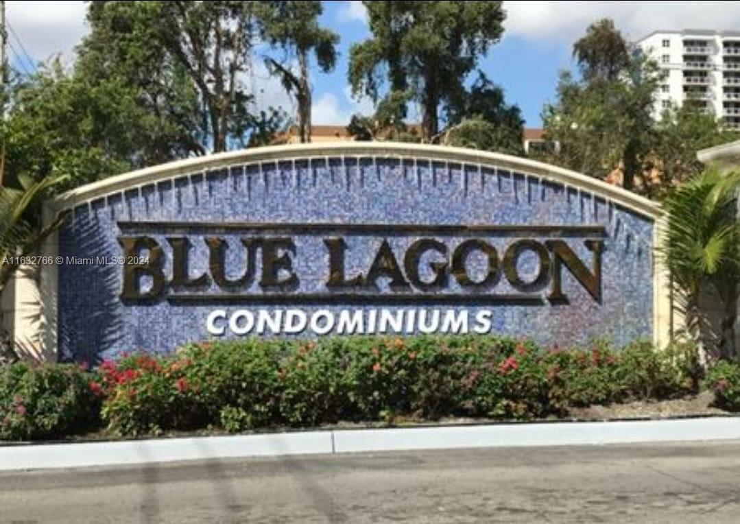 a view of sign board with yard and tree