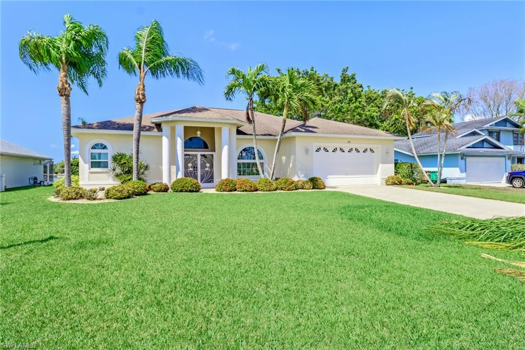 a front view of a house with a yard and palm trees