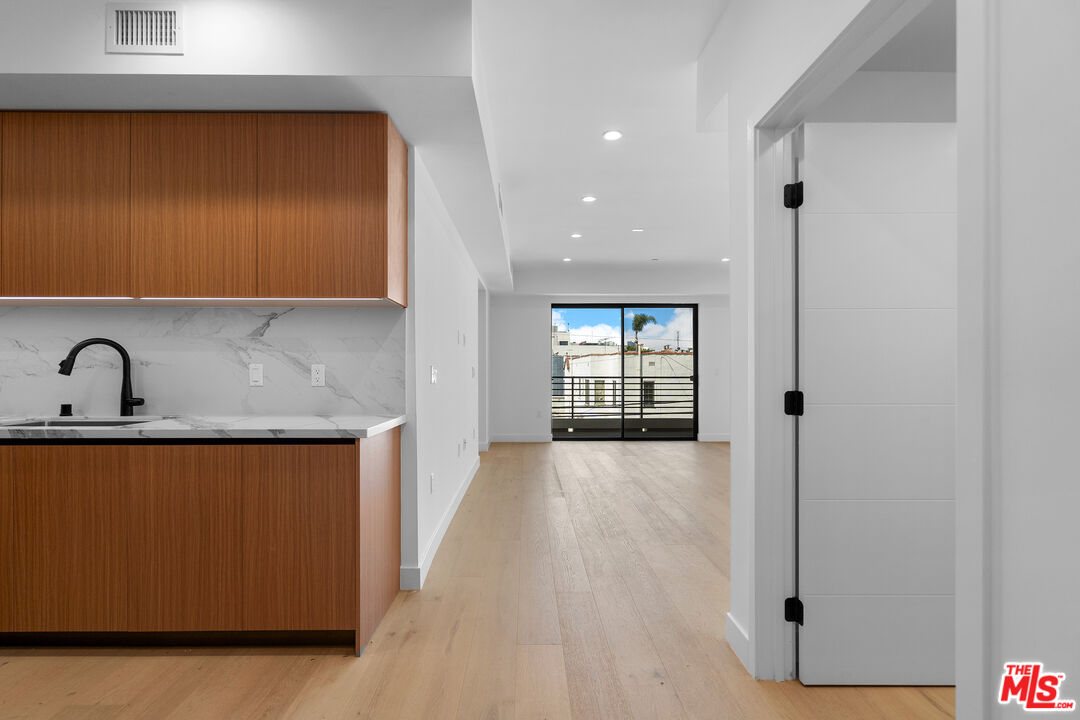 a view of a kitchen with a sink and dishwasher with wooden floor