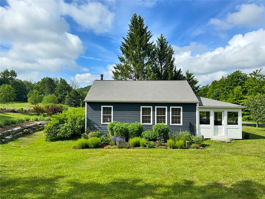 a view of a house with a big yard potted plants and large tree