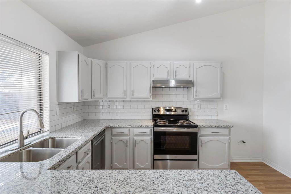 a kitchen with granite countertop a sink stove and cabinets