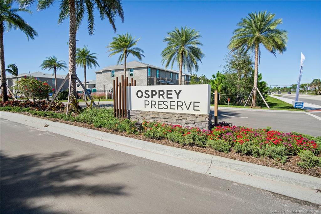 a sign board with flower plants and palm trees